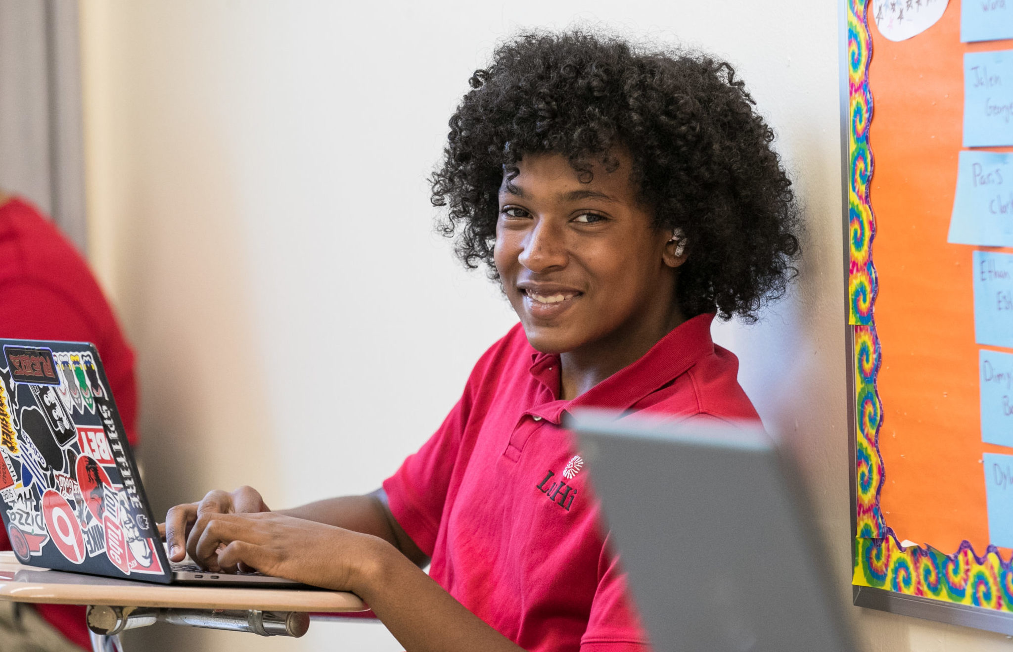 Student smiling in class using his computer