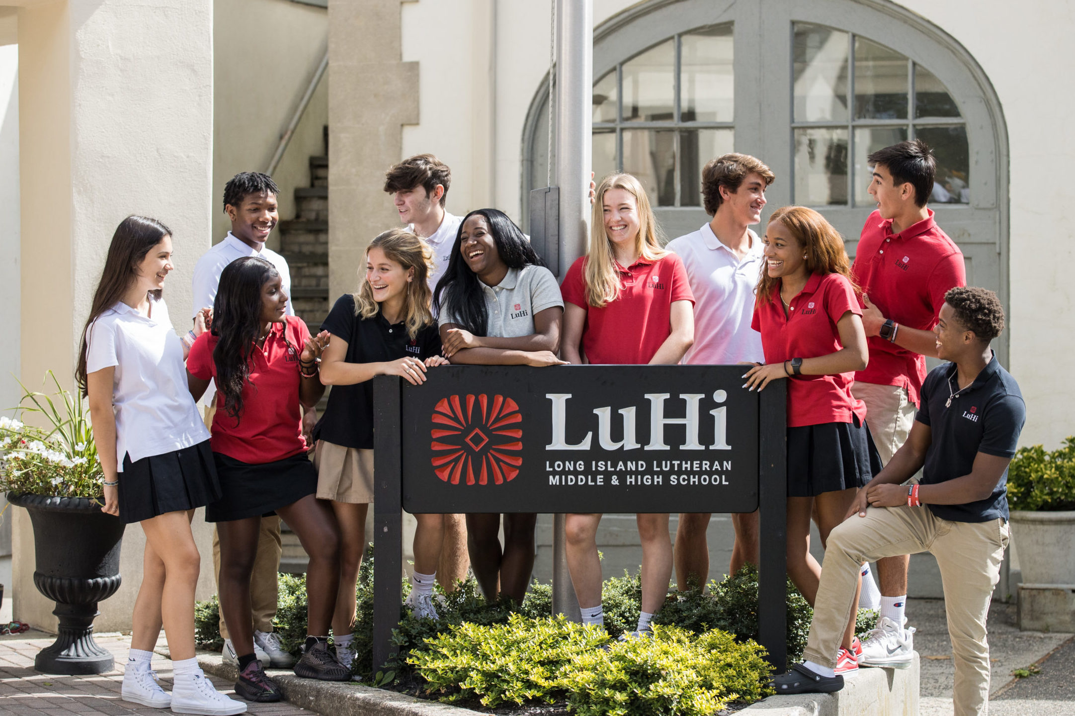 Group of LuHi students laughing around the school sign