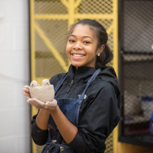 Student displaying work in ceramics class