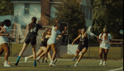 Girls lacrosse players running down field