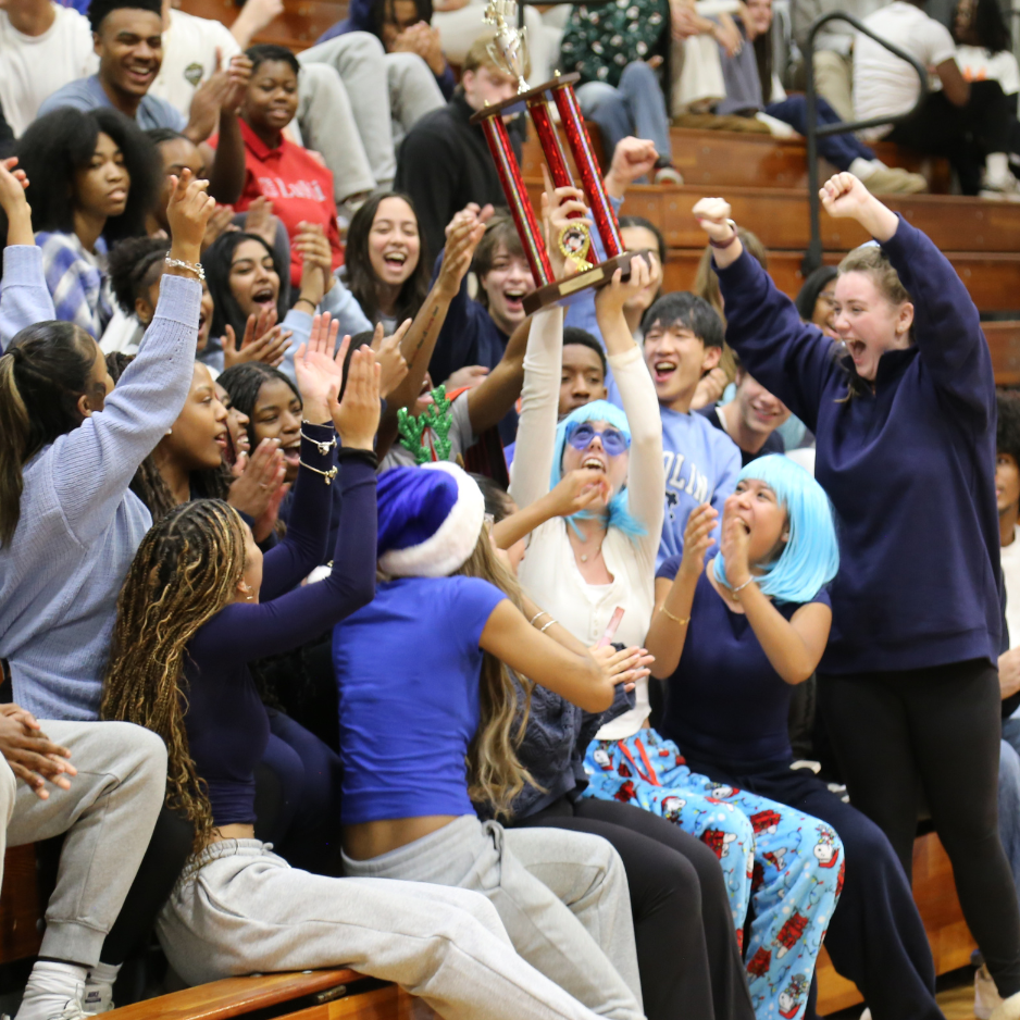 students cheering with a trophy