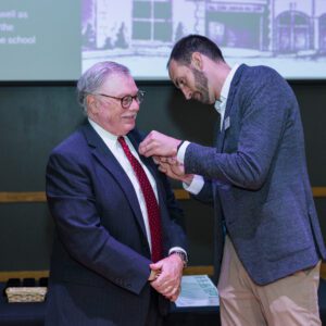 John Buck putting a pin on an award recipient