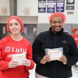 two girls holding packaged rice smiling